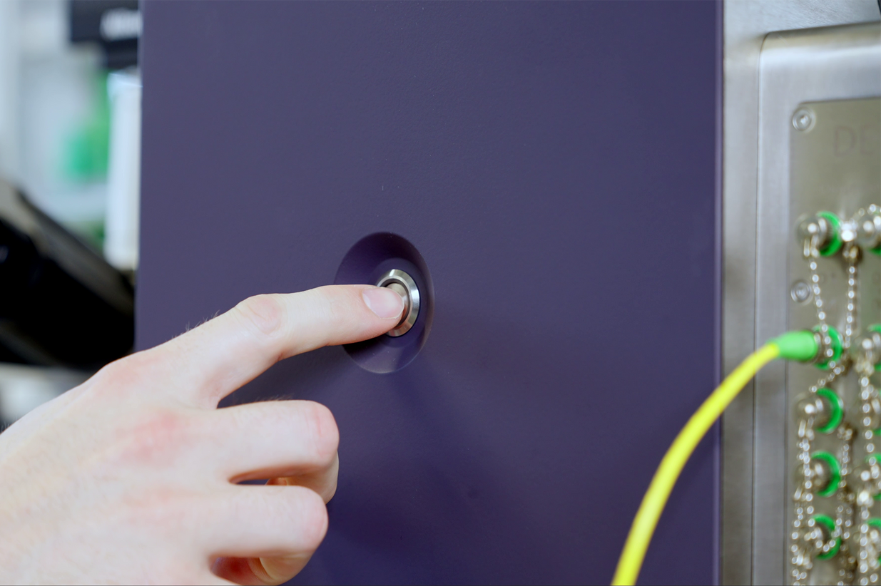 Single_Photon_Detector_SNSPD_Pixel_Photonics Close up of the SNSPD system showing someone pushing the button to start the single photon detector system by Pixel Photonics